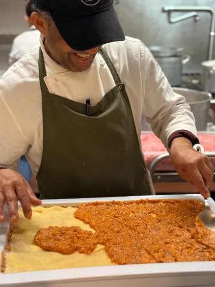A cook preparing a tray of lasagne