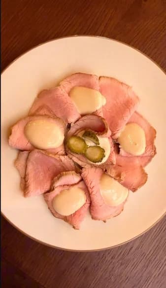 Sliced meat with sauce and gherkins